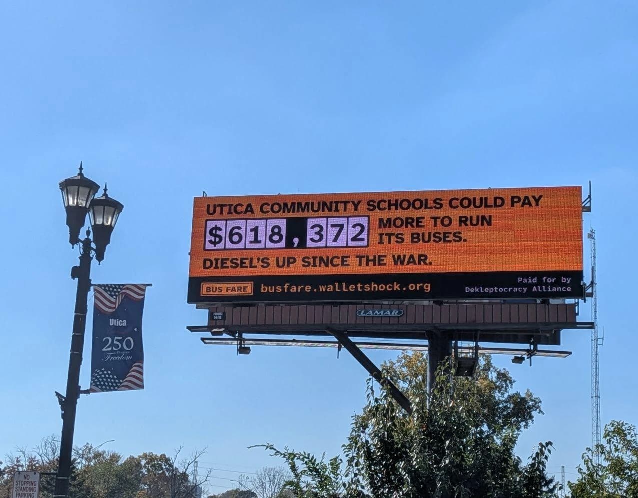 Digital billboard in Utica, Michigan, reading: Utica Community Schools could pay $618,372 more to run its buses. Diesel's up since the war. busfare.walletshock.org. Paid for by Dekleptocracy Alliance.