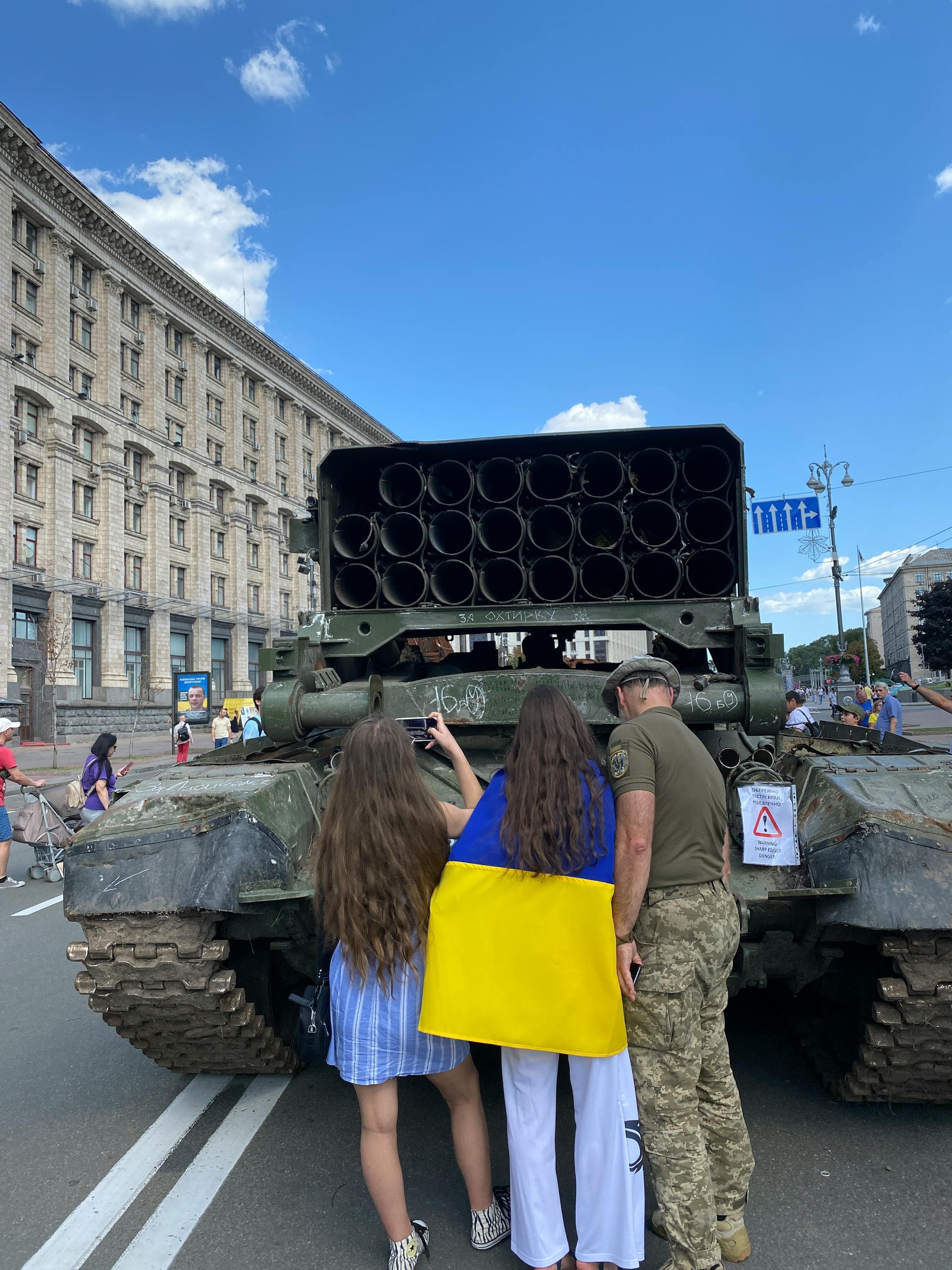 Ukrainian women with national flag next to captured Russian tank, Kyiv